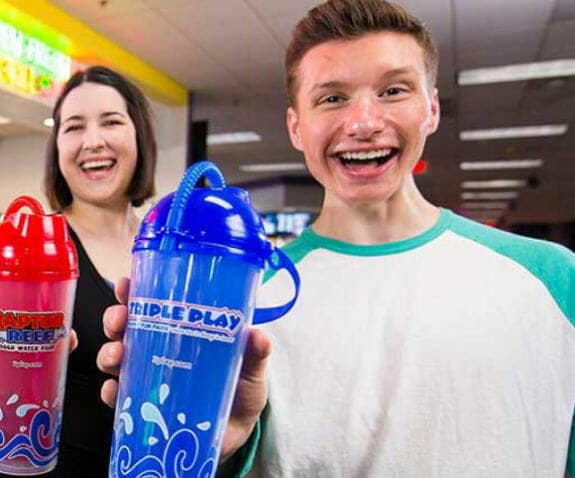 Man and woman holding up their souvenir Triple Play cups
