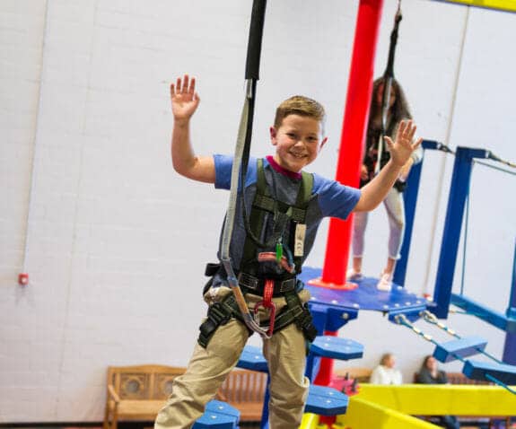 Young boy in a harness on the ropes course