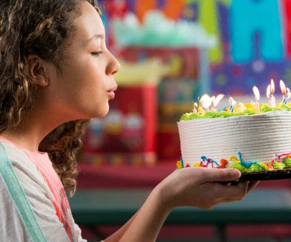 Young girl blowing out candles on a birthday cake