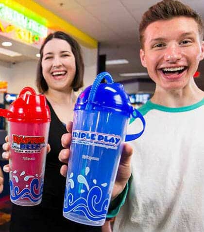 Man and woman holding up their souvenir Triple Play cups