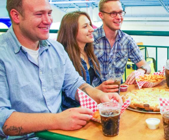 Young professionals sitting at a table eating food and laughing together