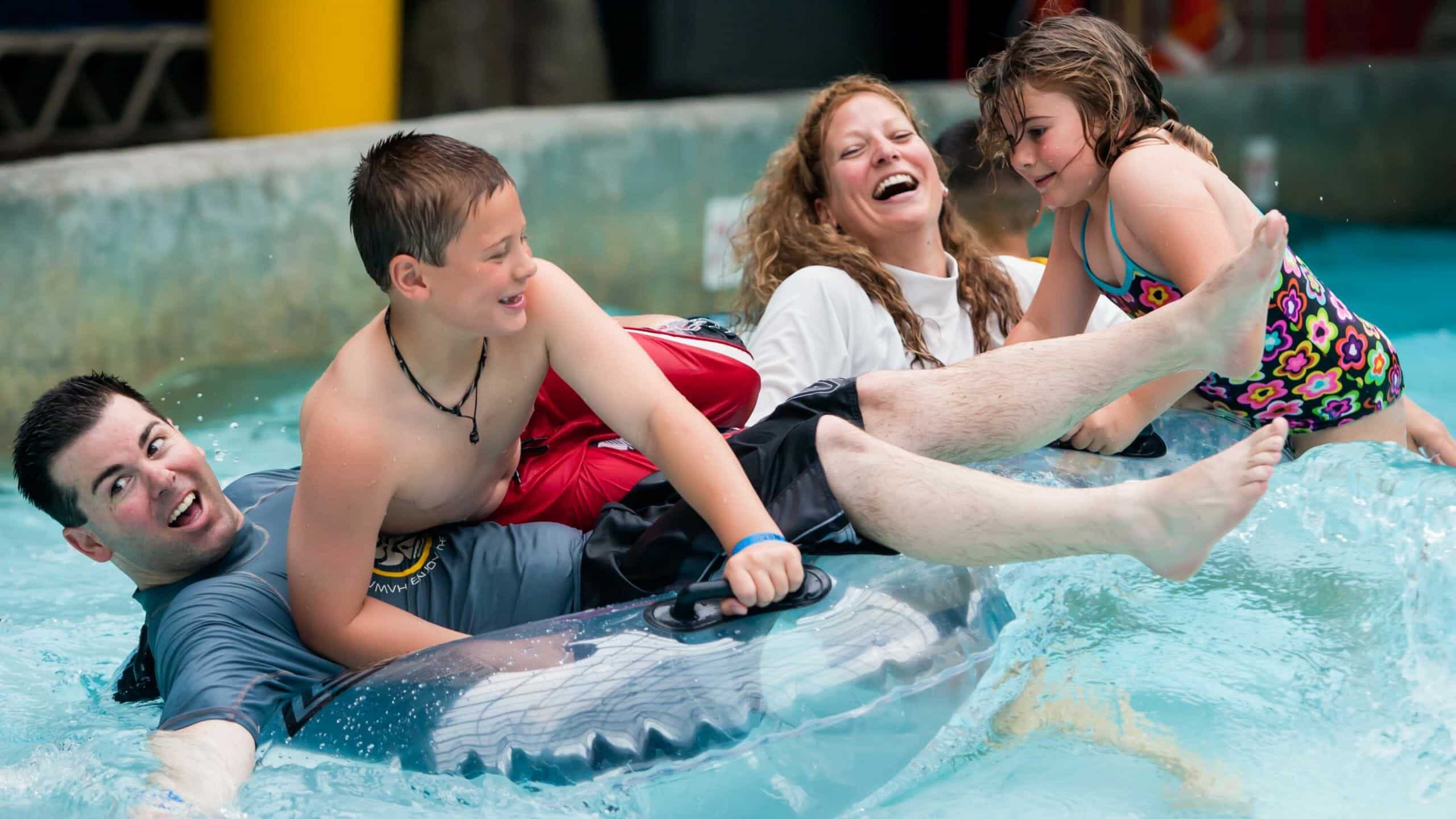Family of four laughing and having fun in the wave pool