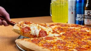 A pizza next to a pitcher of drinks