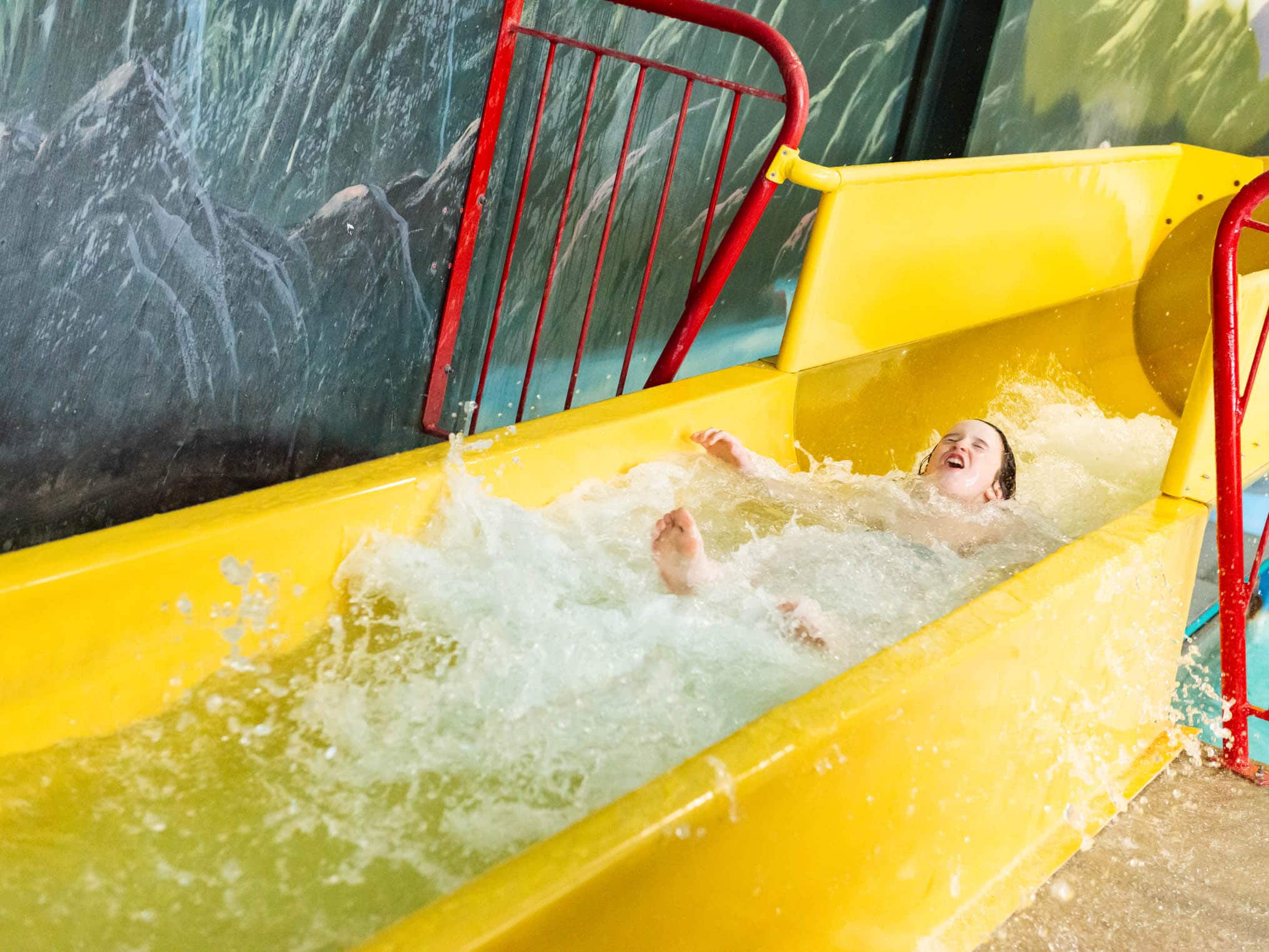 Young boy sliding down the water slide